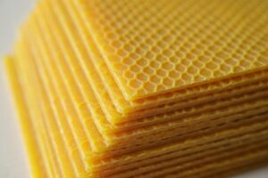 Stack of yellow beeswax foundation sheets with embossed hexagonal cell pattern for Kenyan Langstroth hive frames
